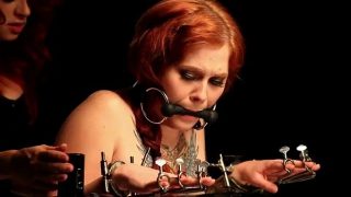 Gagged red head babe in bondage device gets spanked